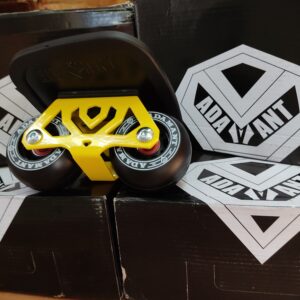 Patines en linia de color amarillo y negro de la modalidad de patinaje freeskates, antes llamado freeline junto a cajas y logotipos de la marca Adamant.